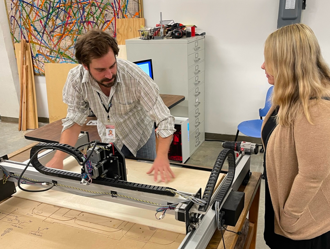 Library employee helping someone with the CNC machine