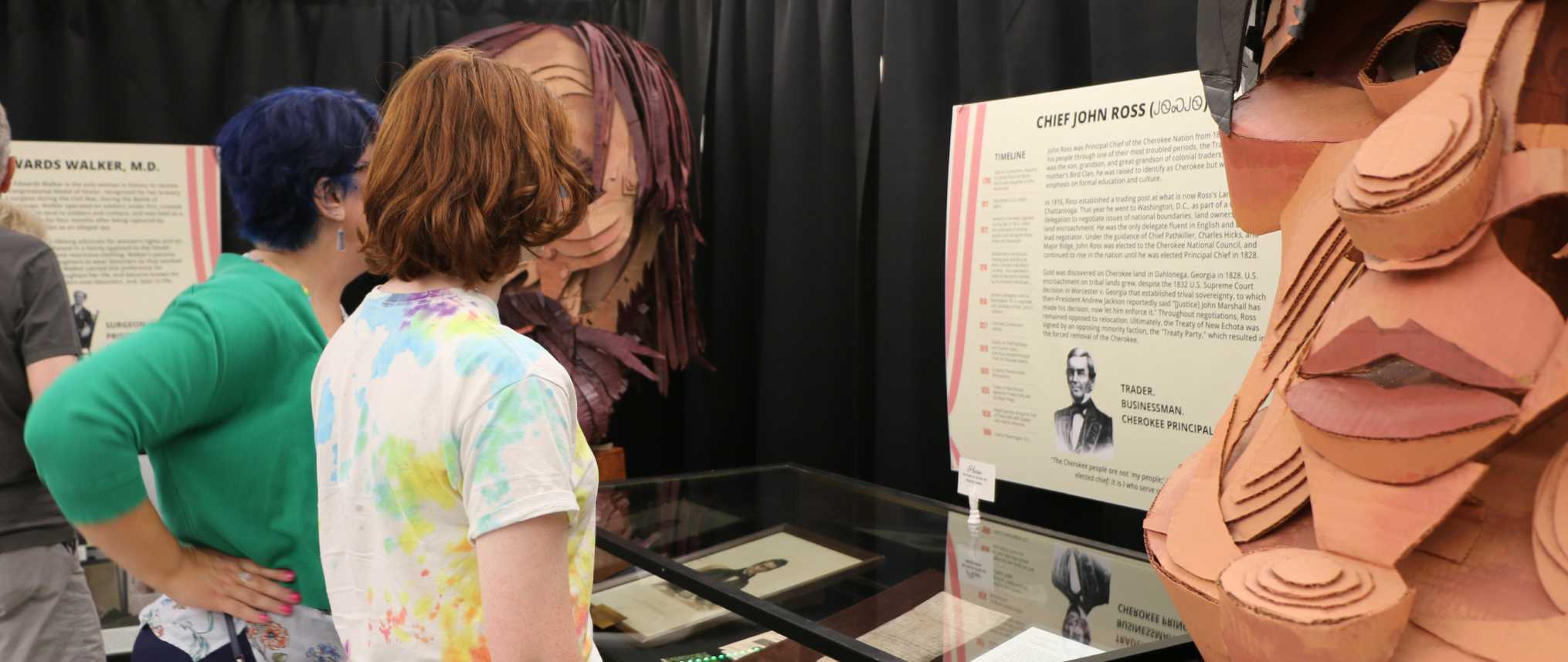People looking at library exhibit featuring Wayne White sculptures and information about Chief John Ross