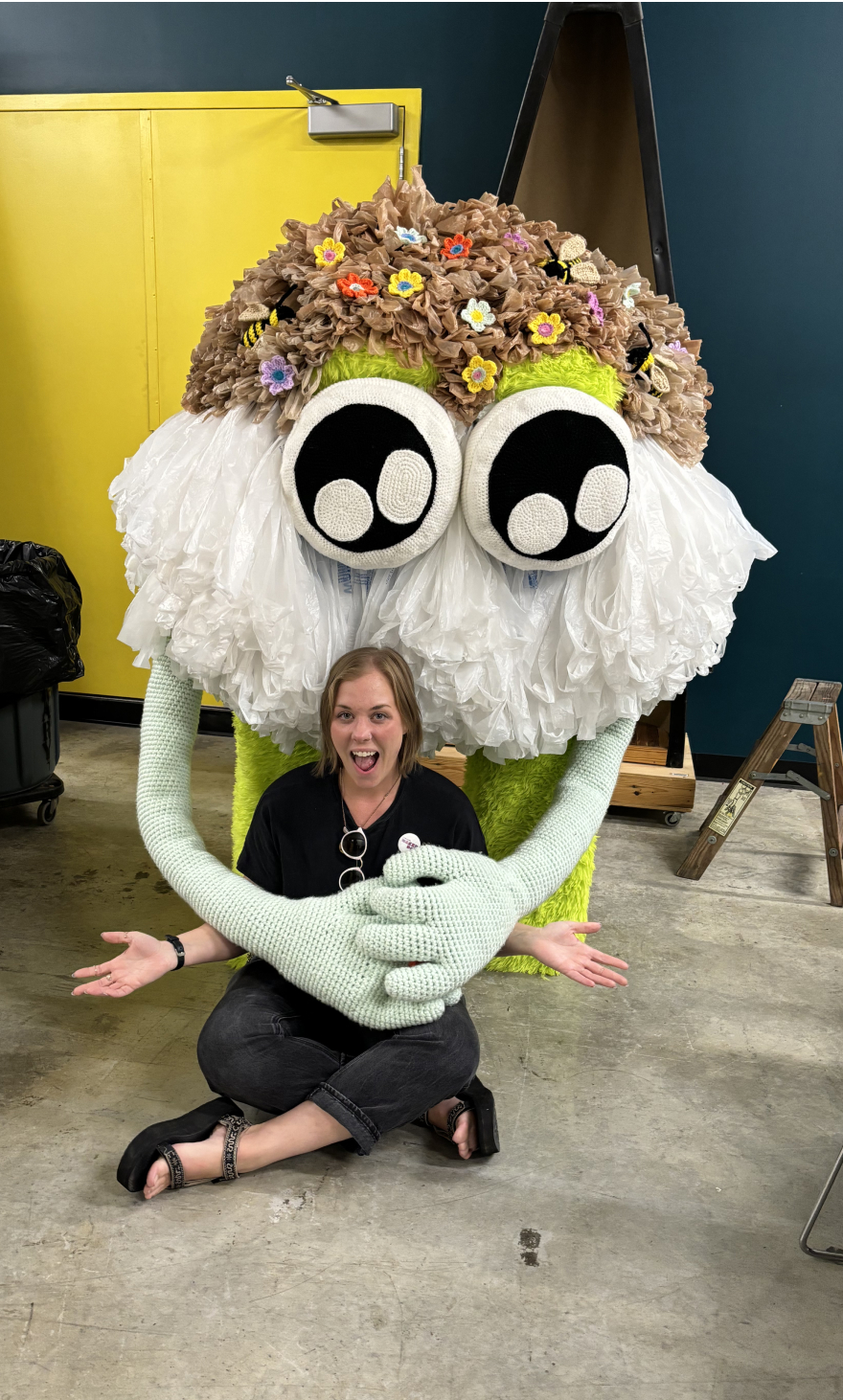woman sitting in front of a large fabric creature sculpture